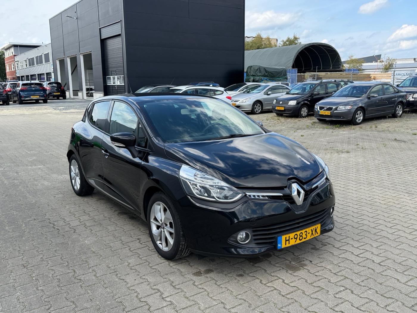 Zwarte Renault Clio driekwart van voren op een dealerterrein, op heuphoogte gefotografeerd met de hele auto in beeld