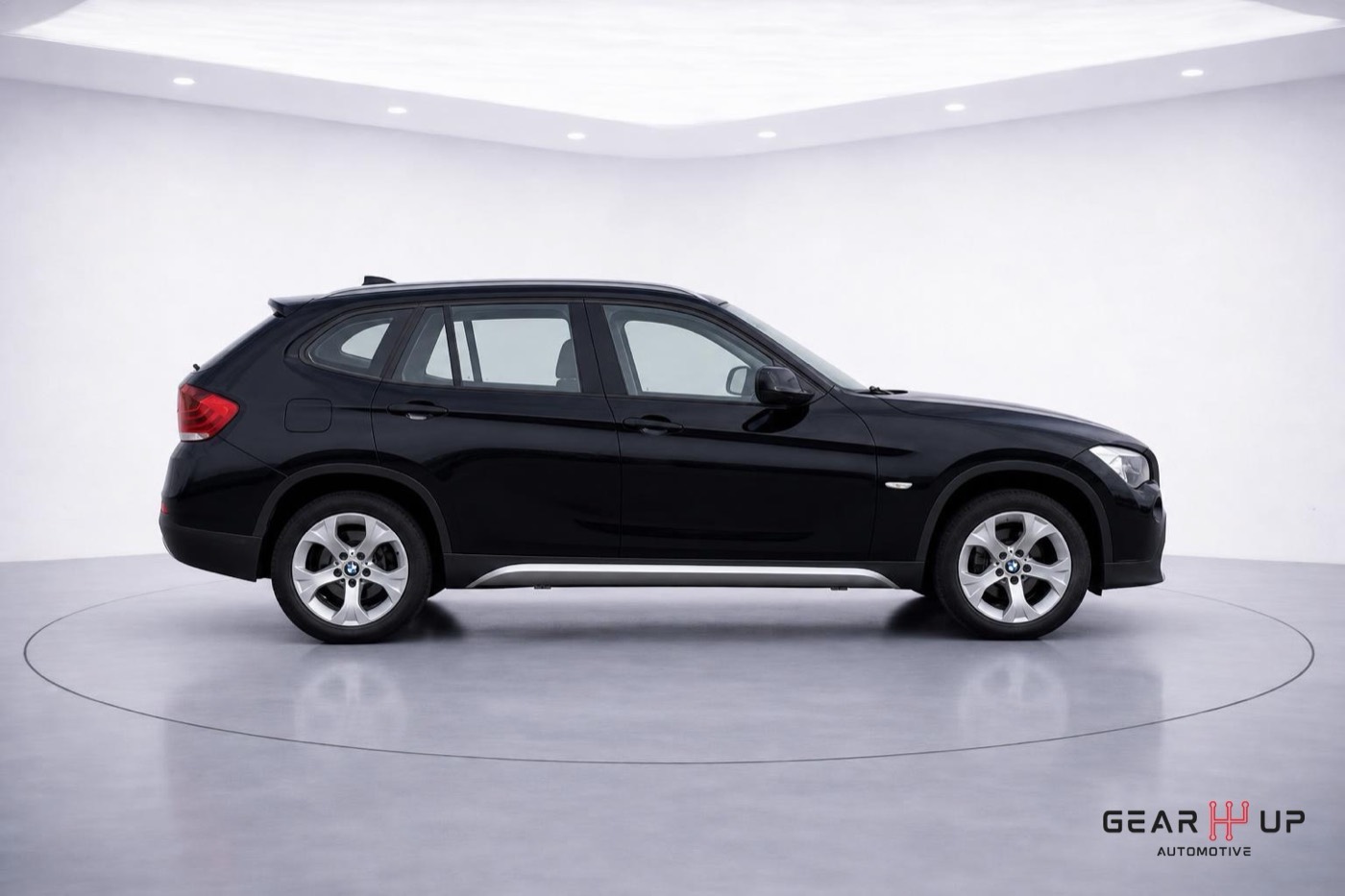 Dezelfde BMW X1 van opzij op een witte studio-achtergrond met schaduw onder de banden